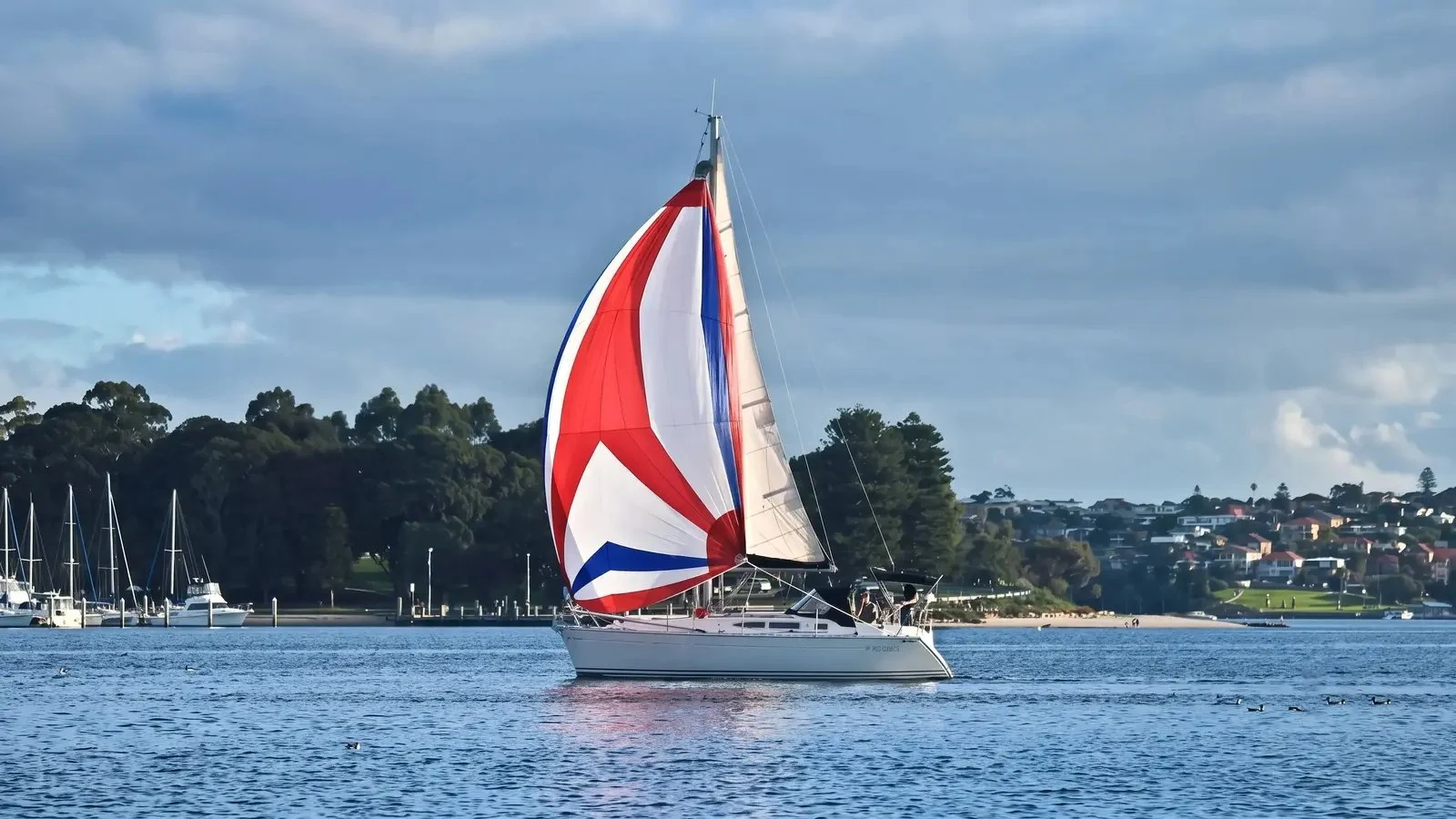 A cruising yacht sailing under a red, white and blue spinnaker